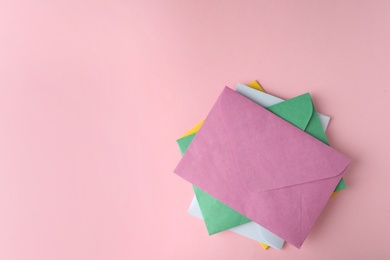 Colorful paper envelopes on pink background, flat lay. Space for text