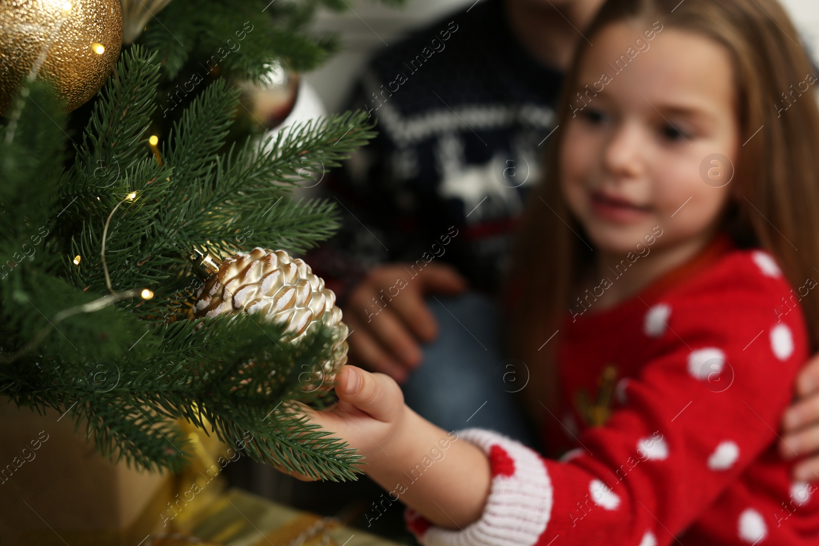 Photo of Cute little girl near Christmas tree, focus on hand
