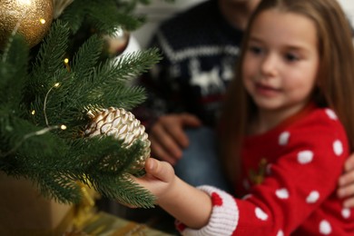 Cute little girl near Christmas tree, focus on hand