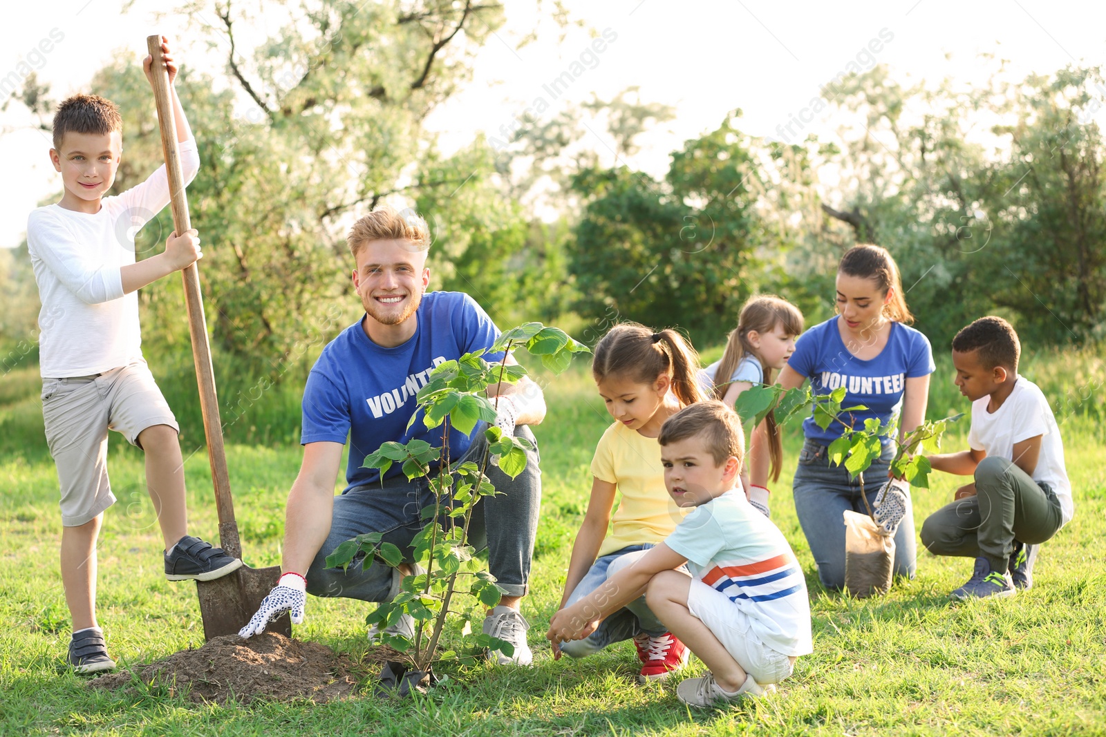 Photo of Kids planting trees with volunteers in park