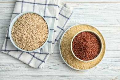 Flat lay composition with different types of rice on wooden table