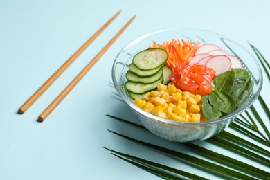 Delicious salad with salmon, vegetables and rice on turquoise background
