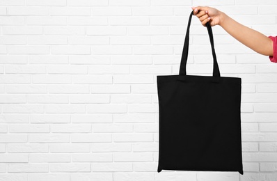 Photo of Woman with stylish blank eco bag near brick wall, closeup. Space for text