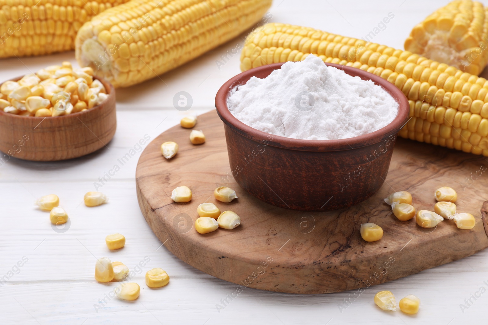 Photo of Bowl with corn starch and kernels on white wooden table