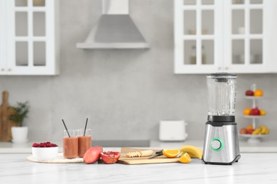 Blender, tasty smoothie and ingredients on white marble table in kitchen