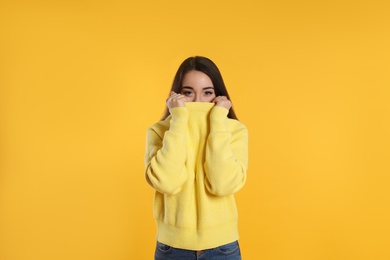 Photo of Beautiful young woman wearing warm sweater on yellow background