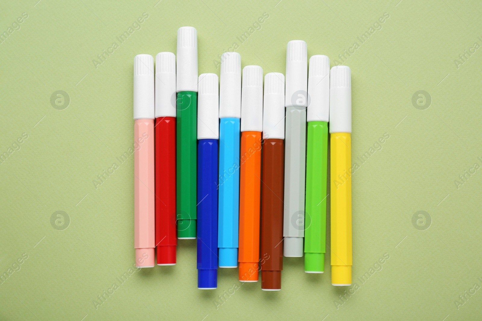 Photo of Different colorful markers on light green background, flat lay