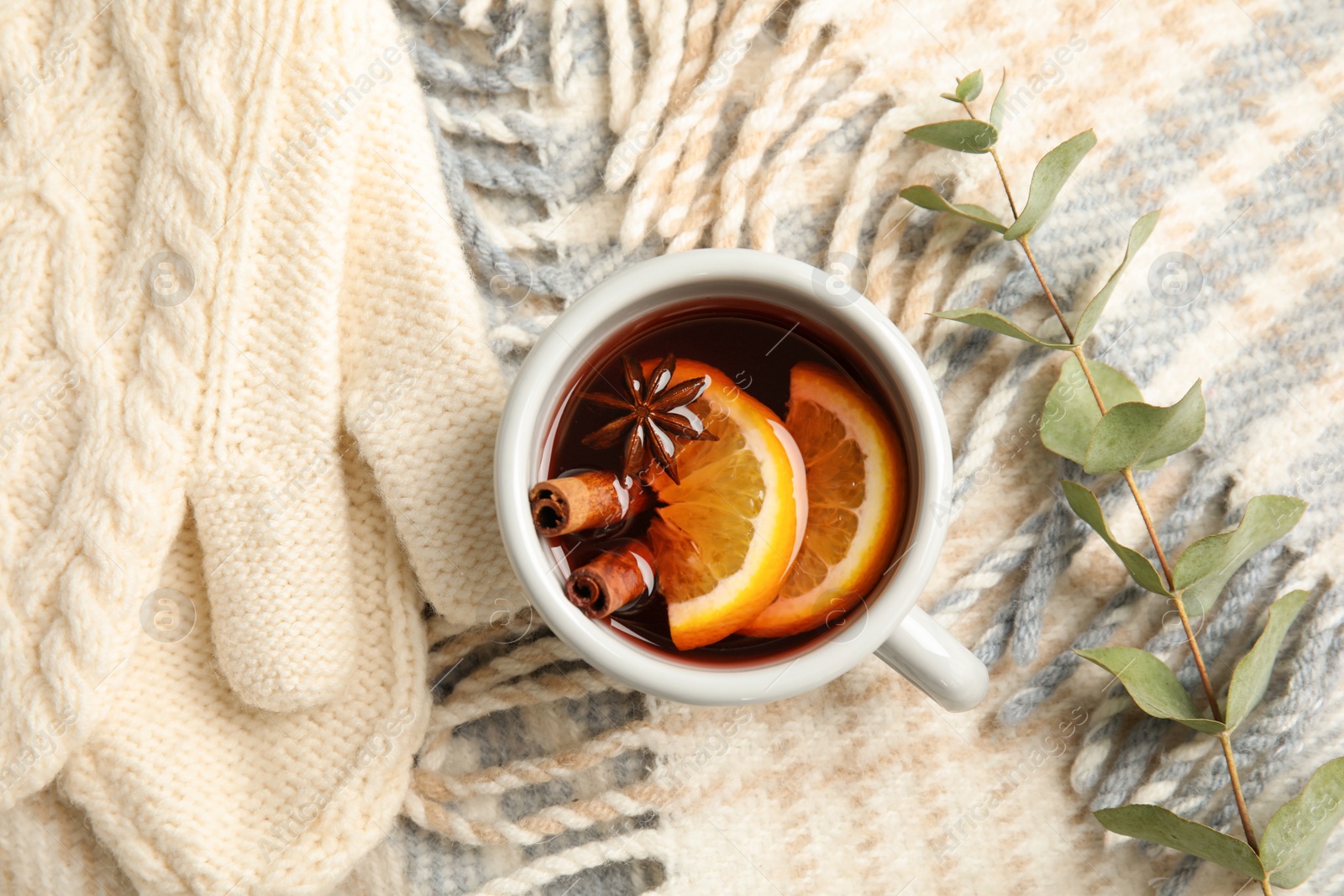 Photo of Composition with cup of hot winter drink and knitted mittens on warm plaid. Cozy season