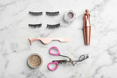 Flat lay composition with magnetic eyelashes and accessories on white marble table