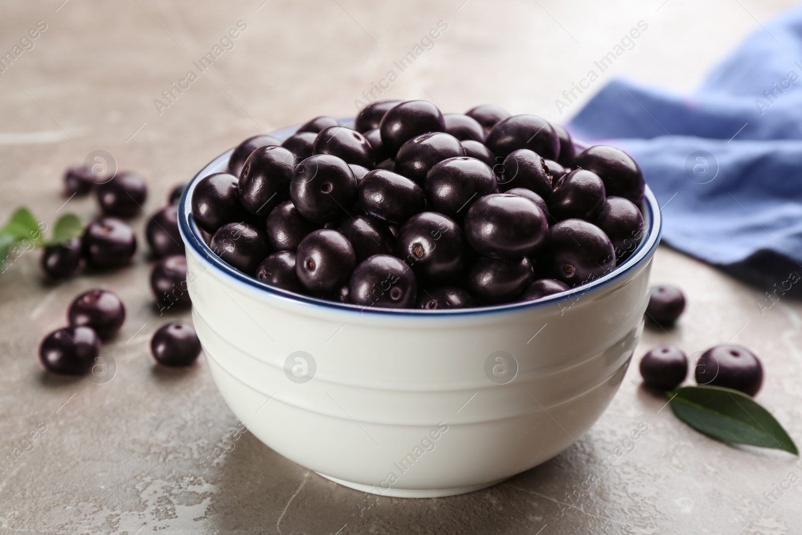 Photo of Fresh acai berries in bowl on light marble table, closeup