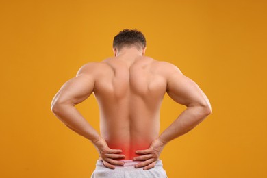 Image of Man suffering from pain in lower back on orange background