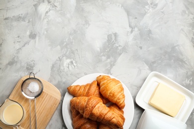 Photo of Plate of fresh croissants served on grey table, flat lay with space for text. French pastry