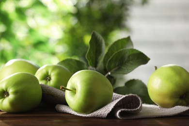 Photo of Fresh ripe green apples and leaves on wooden table outdoors