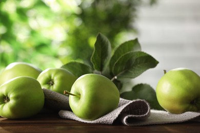 Fresh ripe green apples and leaves on wooden table outdoors