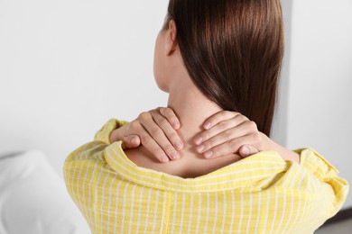 Woman suffering from neck pain indoors, closeup