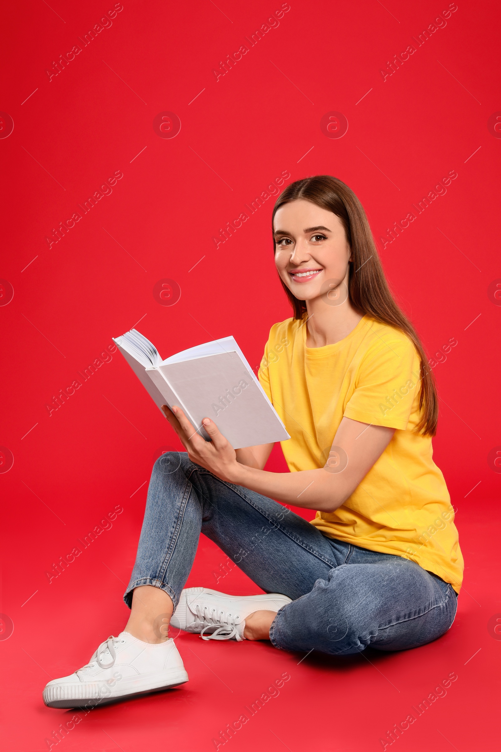 Photo of Young woman reading book on color background, space for text