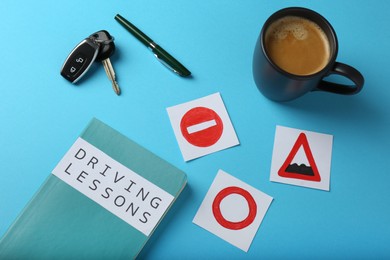 Photo of Composition with workbook for driving lessons on light blue background, above view. Passing license exam