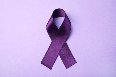 Photo of Purple ribbon on lilac background, top view. Domestic violence awareness