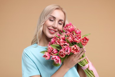 Happy young woman with beautiful bouquet on beige background