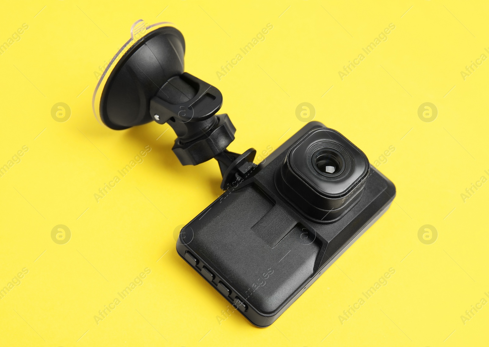 Photo of Modern car dashboard camera with suction mount on yellow background