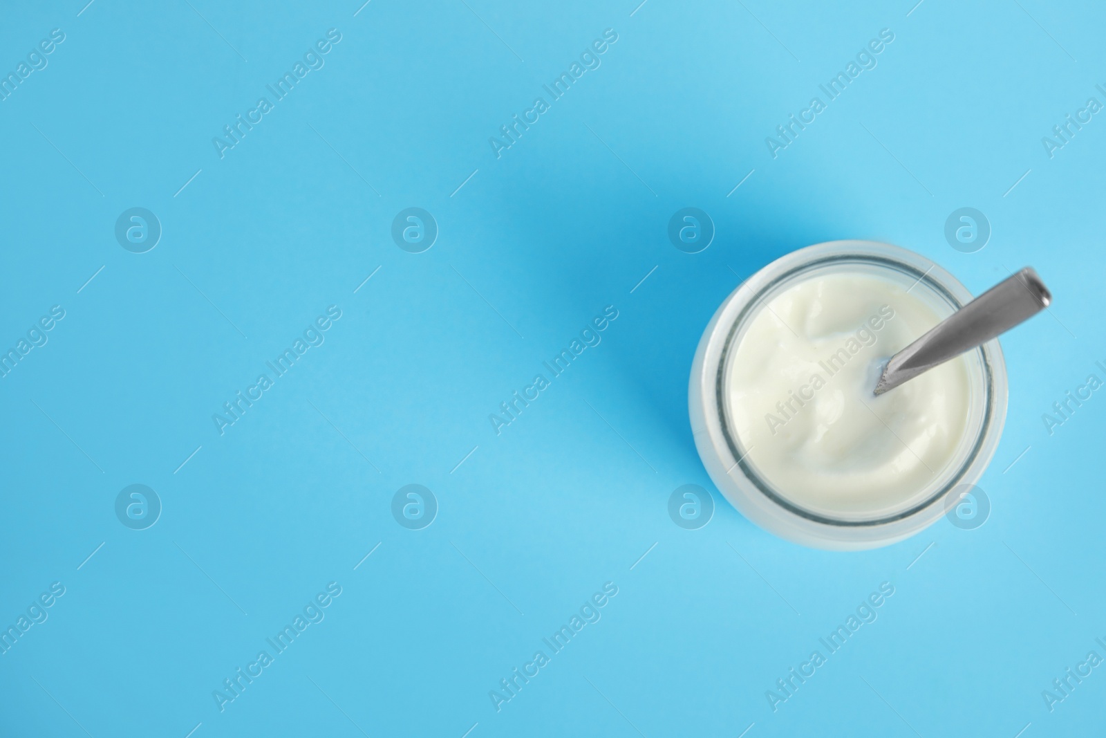 Photo of Tasty organic yogurt on light blue background, top view. Space for text