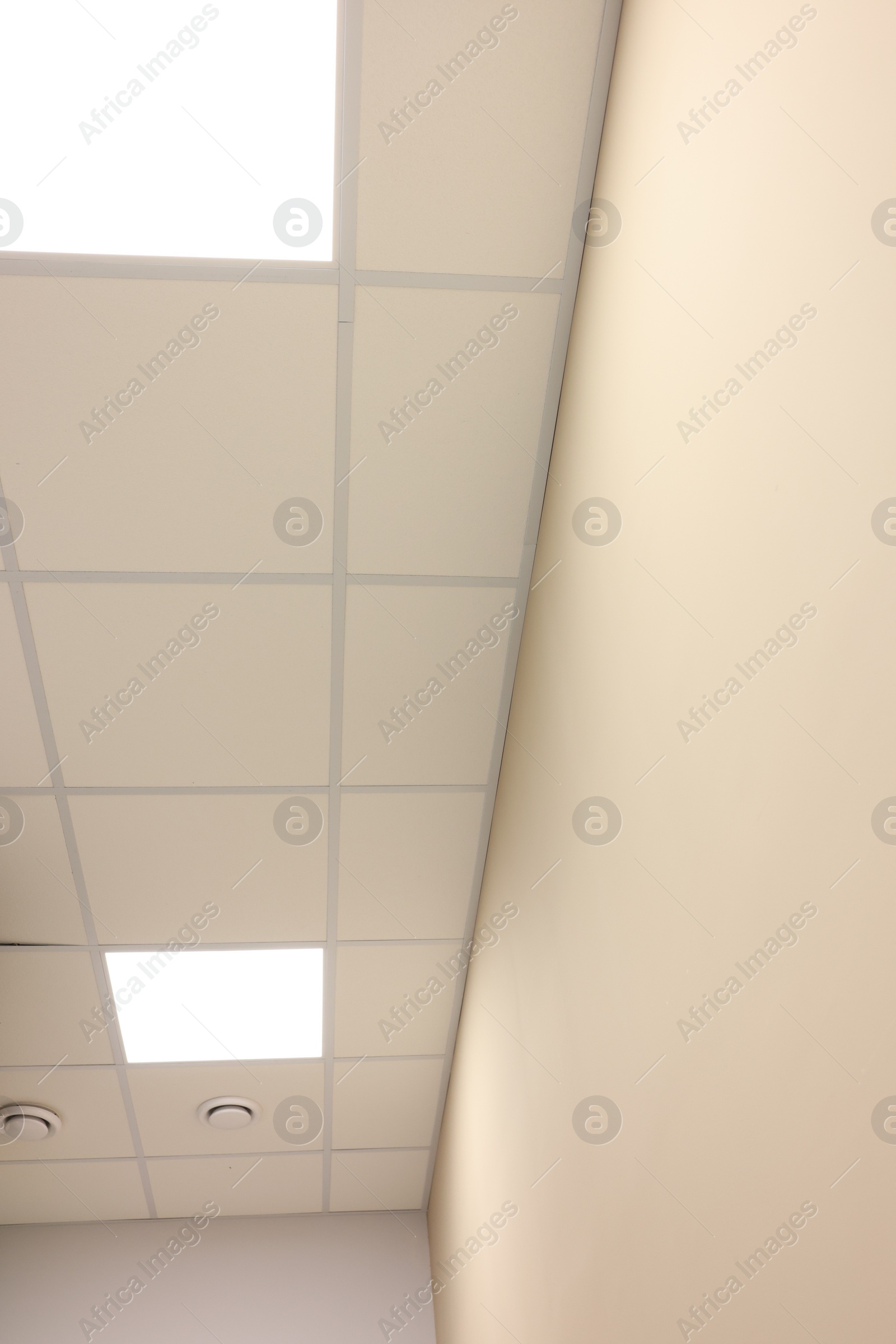 Photo of White ceiling with PVC tiles and lighting indoors, bottom view