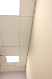 Photo of White ceiling with PVC tiles and lighting indoors, bottom view