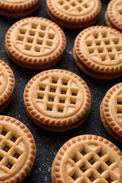 Photo of Tasty sandwich cookies with cream on black textured background, closeup