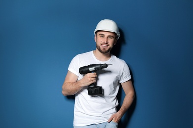 Photo of Young working man with electric screwdriver on color background