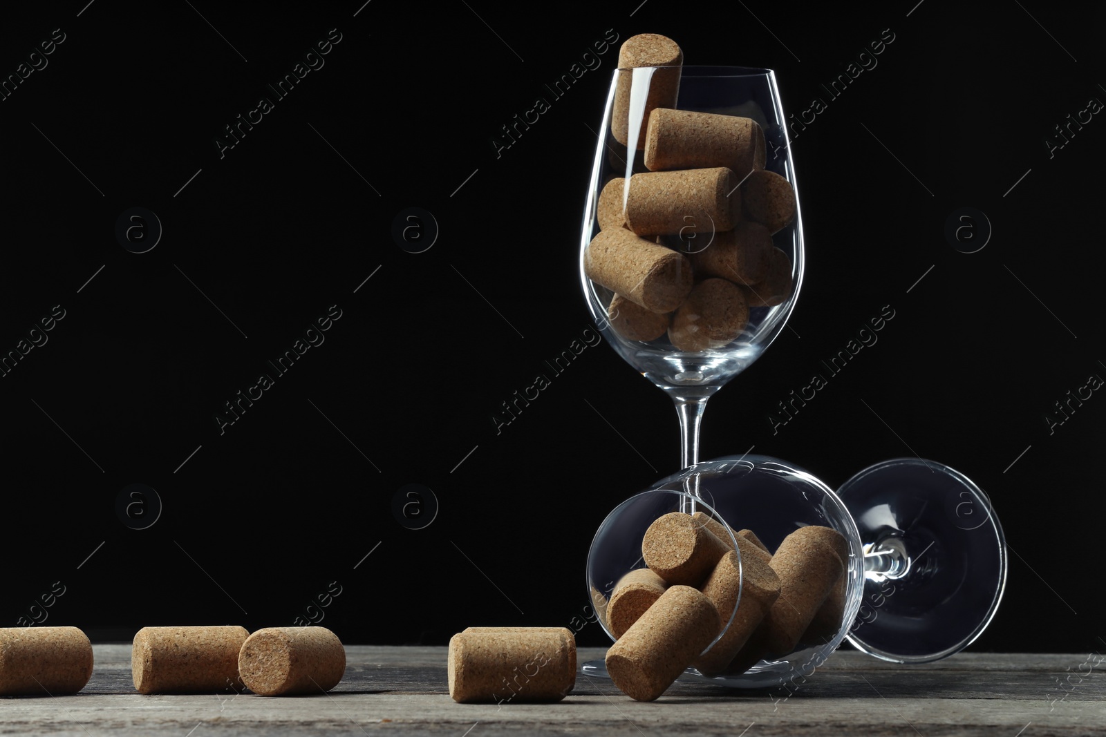 Photo of Glasses with wine corks on wooden table. Space for text