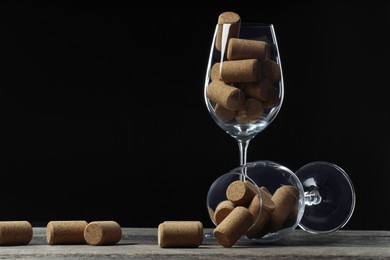 Glasses with wine corks on wooden table. Space for text