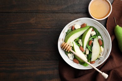 Photo of Delicious pear salad in bowl, honey and dipper on wooden table, top view. Space for text