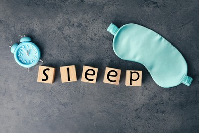 Photo of Word Sleep made of wooden cubes near blindfold and alarm clock on grey background, flat lay. Insomnia concept