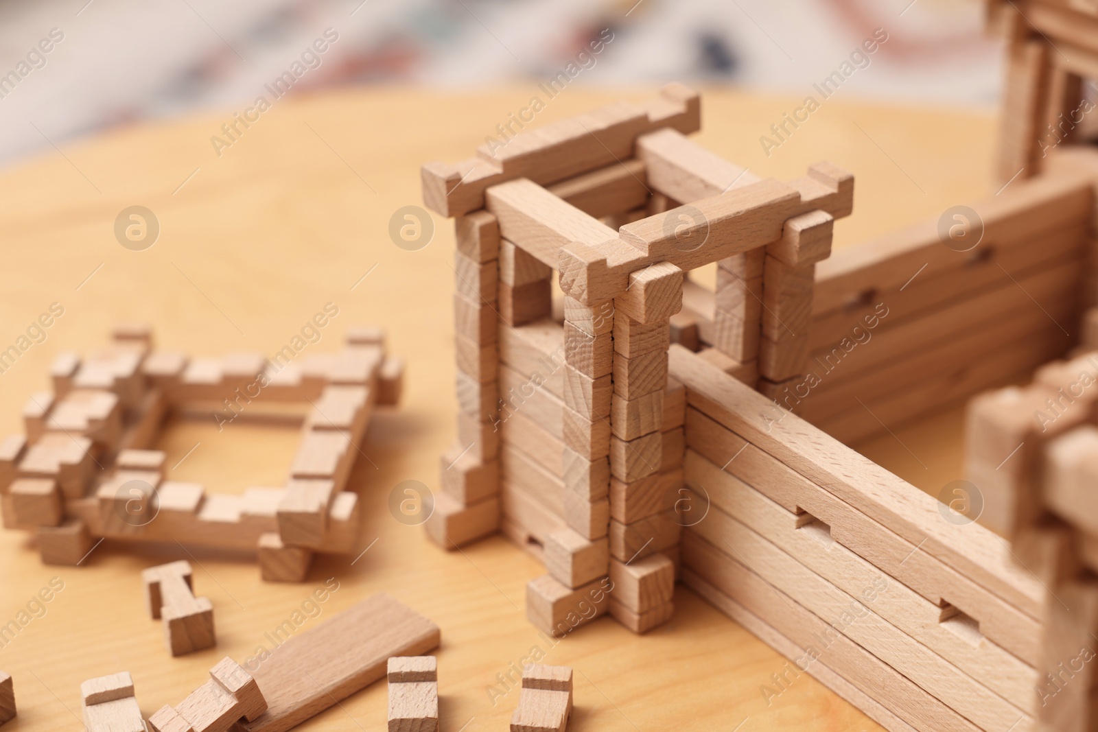 Photo of Wooden fortress and building blocks on table, closeup. Children's toy