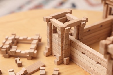 Photo of Wooden fortress and building blocks on table, closeup. Children's toy