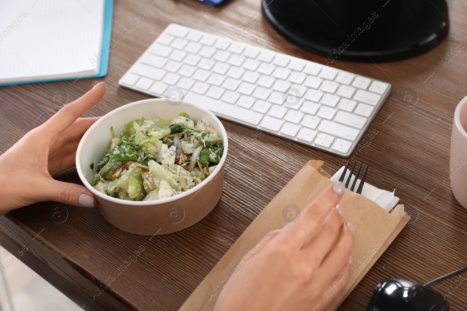 Photo of Office employee having salad for lunch at workplace, closeup. Food delivery