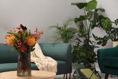 Vase with bouquet of beautiful flowers on table in living room, space for text