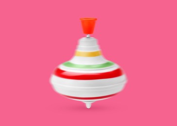 Image of One spinning top in motion on pink background. Toy whirligig