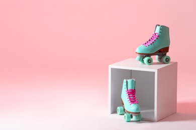 Photo of Pair of vintage roller skates and storage cube on color background. Space for text