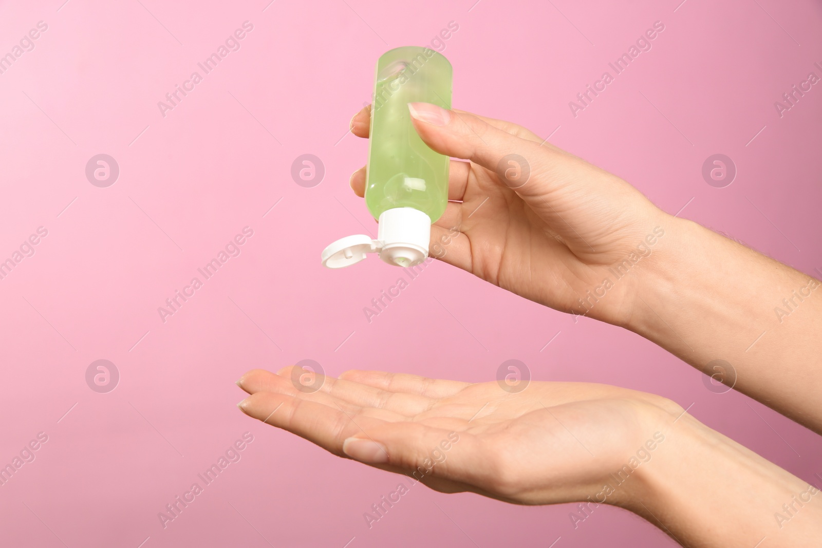 Photo of Woman applying antiseptic gel on pink background, closeup