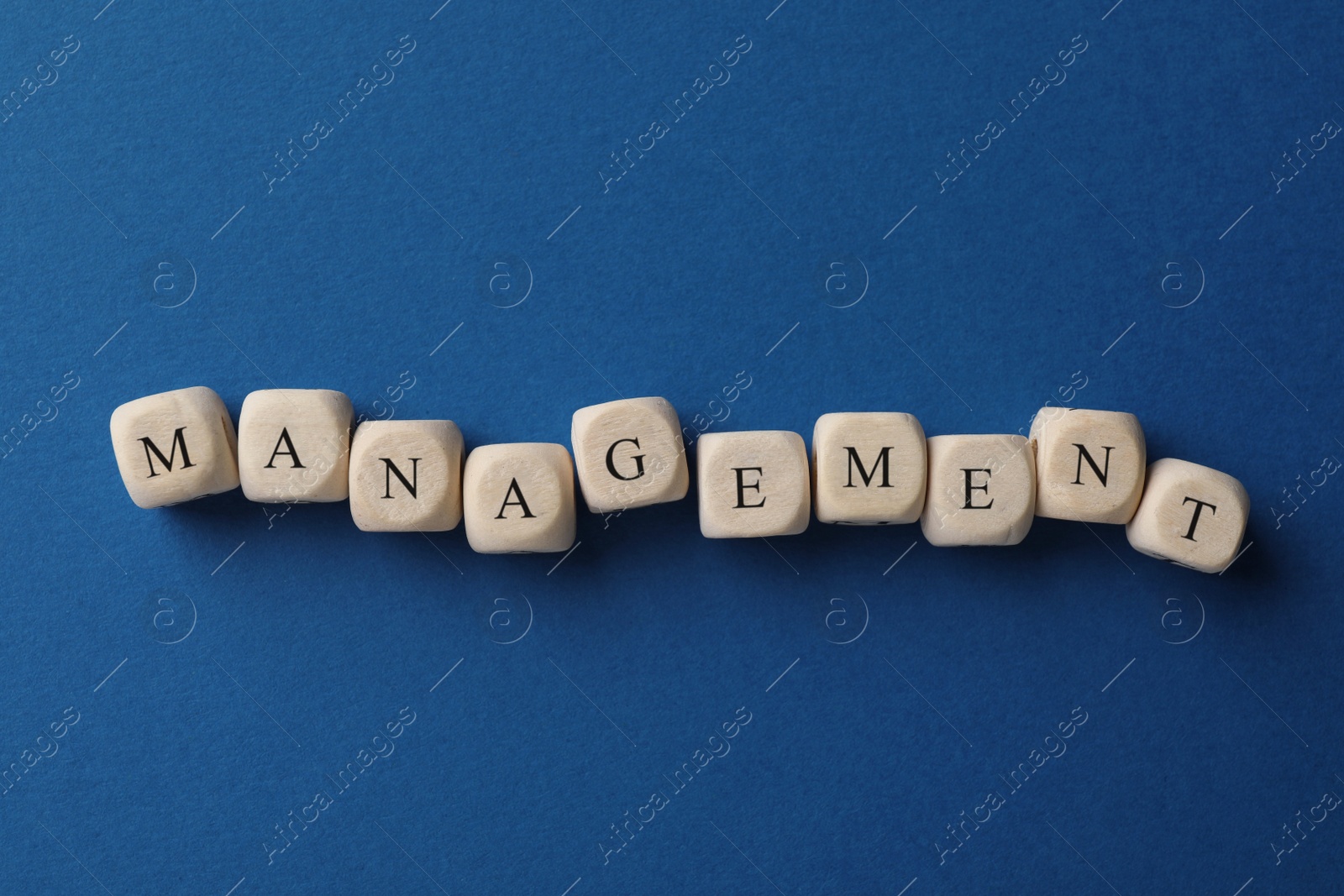 Photo of Word Management made of wooden cubes on blue background, flat lay