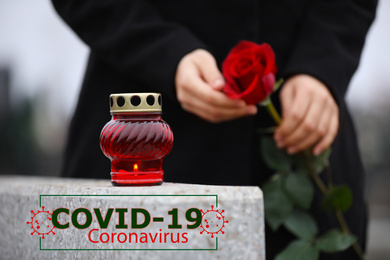 Funeral ceremony devoted to coronavirus victims. Woman holding rose near tombstone with candle outdoors, closeup