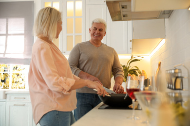 Photo of Mature couple cooking food together in kitchen