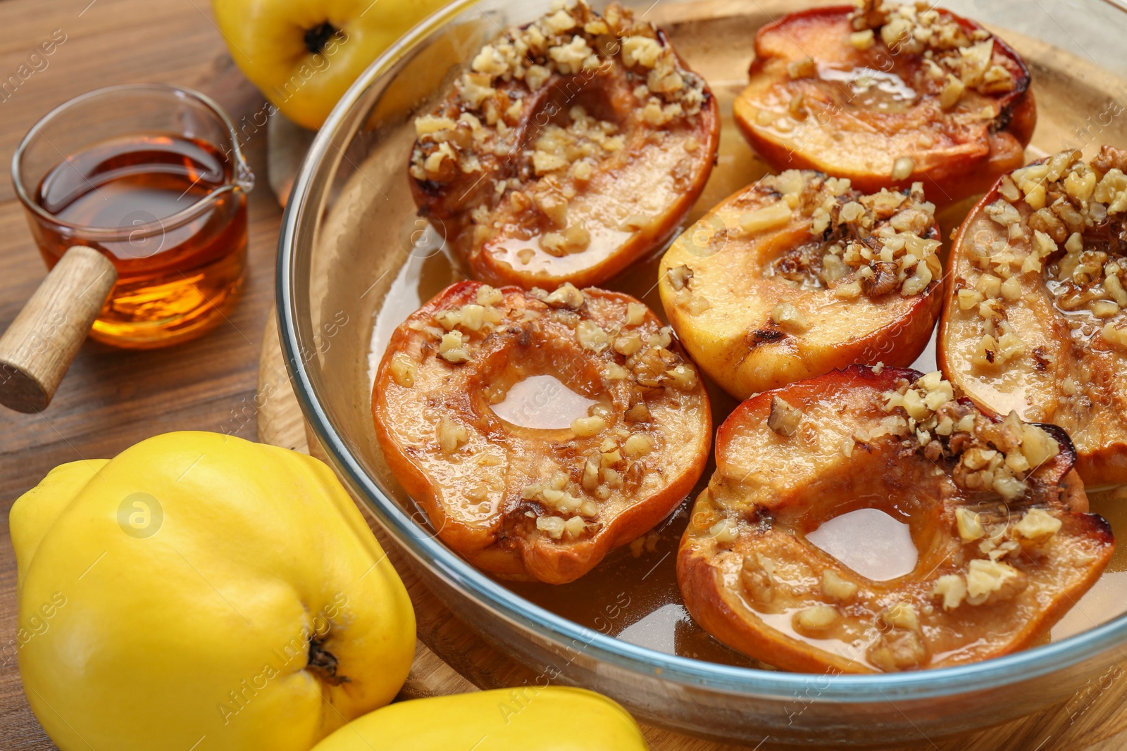 Photo of Tasty baked quinces with walnuts and honey in bowl on wooden table, closeup