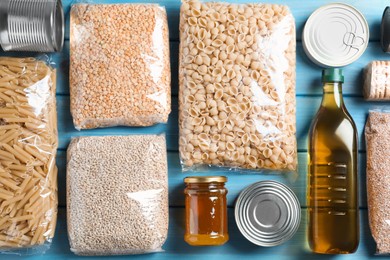 Photo of Different products on turquoise wooden table, flat lay. Food donation