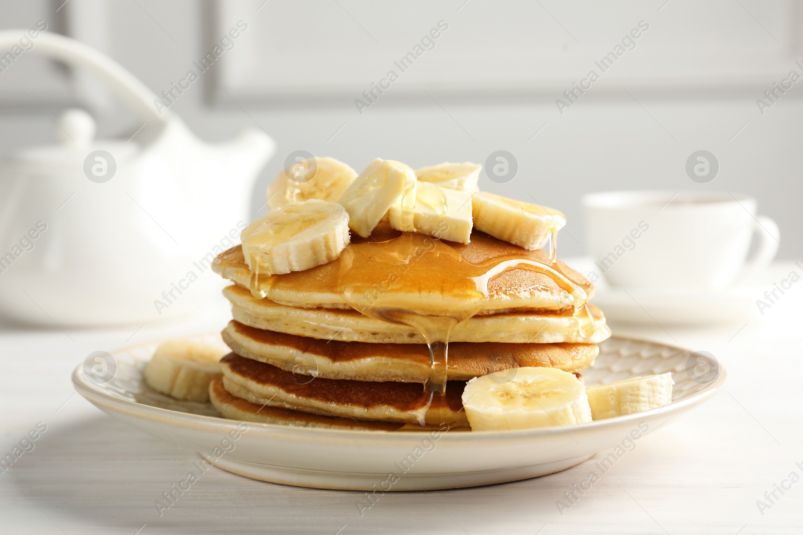 Photo of Delicious pancakes with bananas, honey and butter on white wooden table, closeup