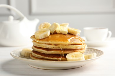 Photo of Delicious pancakes with bananas, honey and butter on white wooden table, closeup