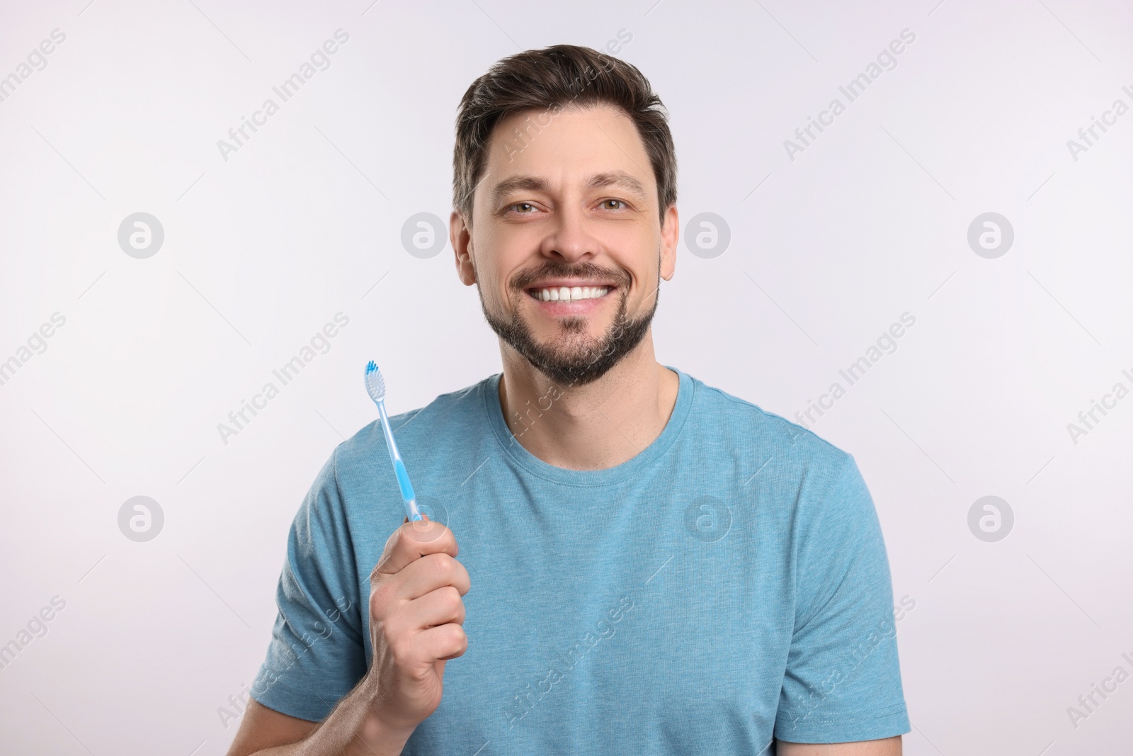 Photo of Happy man holding plastic toothbrush on white background. Mouth hygiene