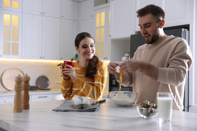 Photo of Lovely young couple cooking dough together in kitchen