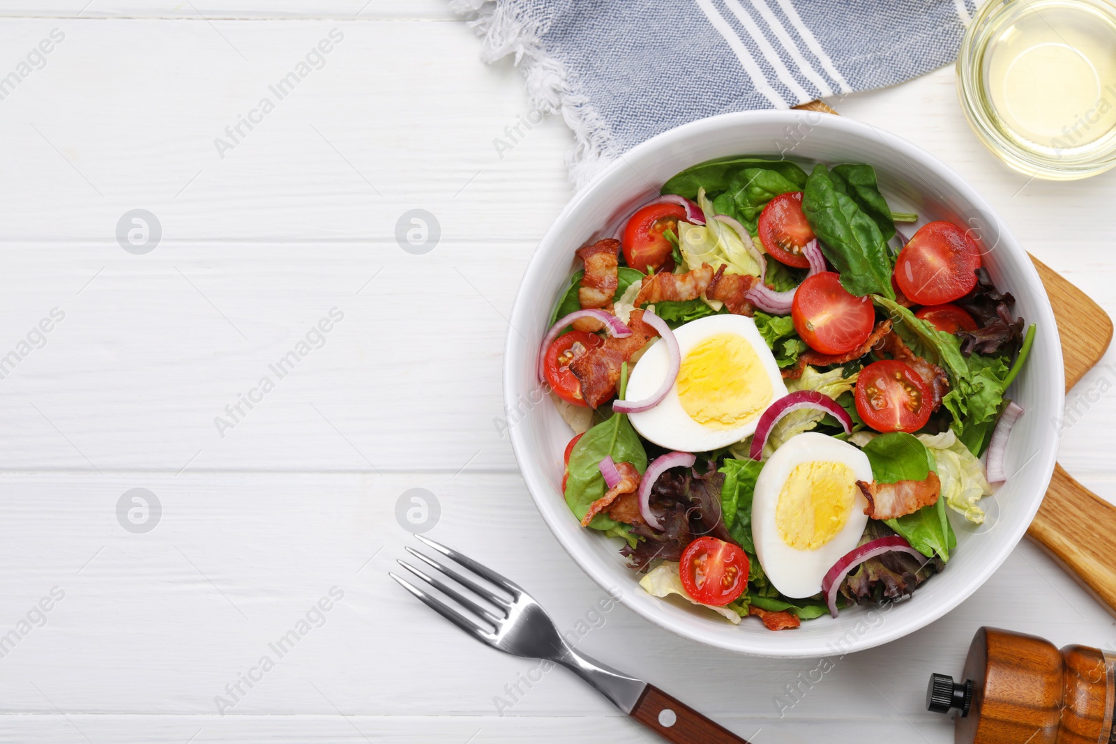 Photo of Delicious salad with boiled egg, bacon and vegetables served on white wooden table, flat lay. Space for text